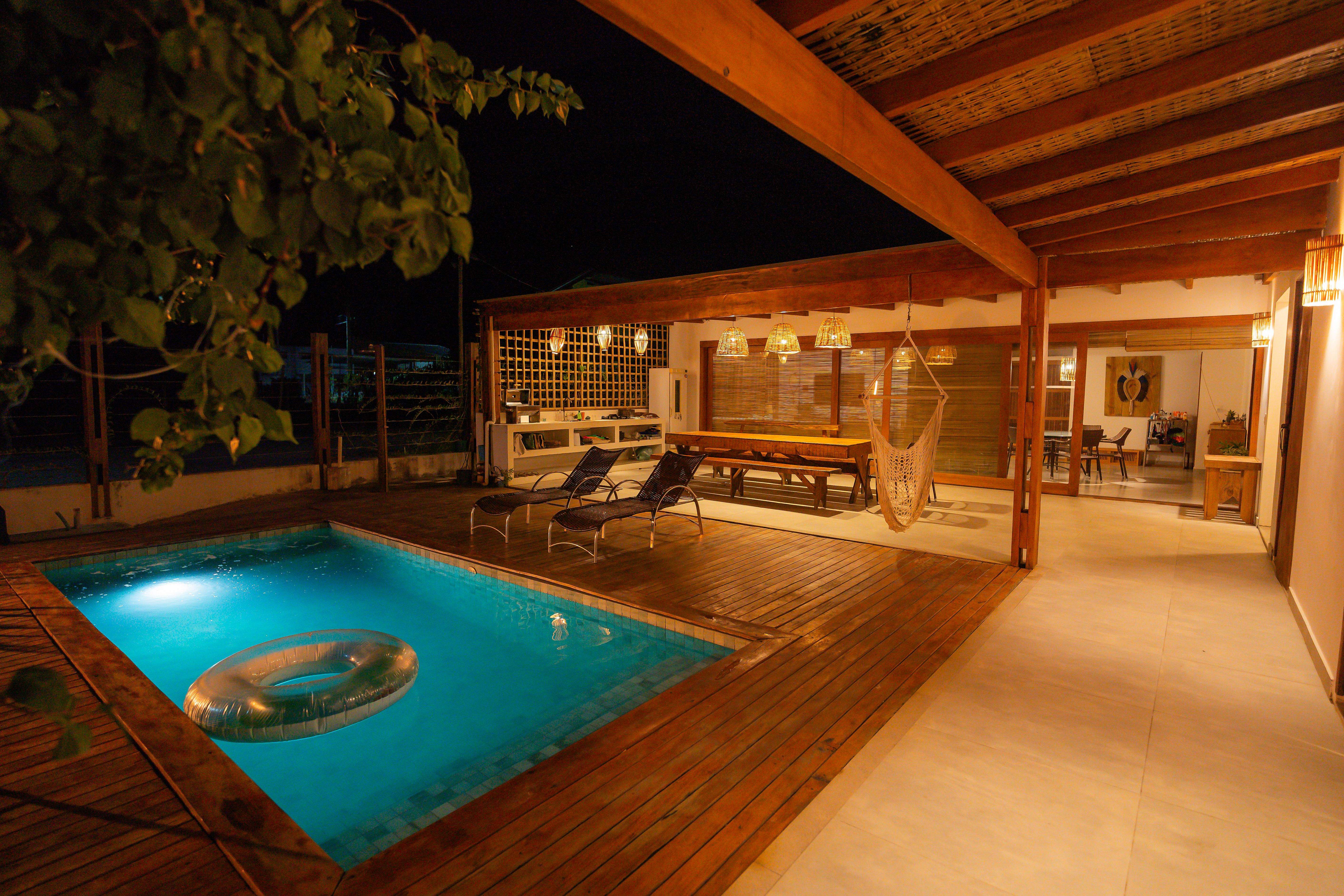 Pátio interno da Casa Orybá com deck de madeira e piscina